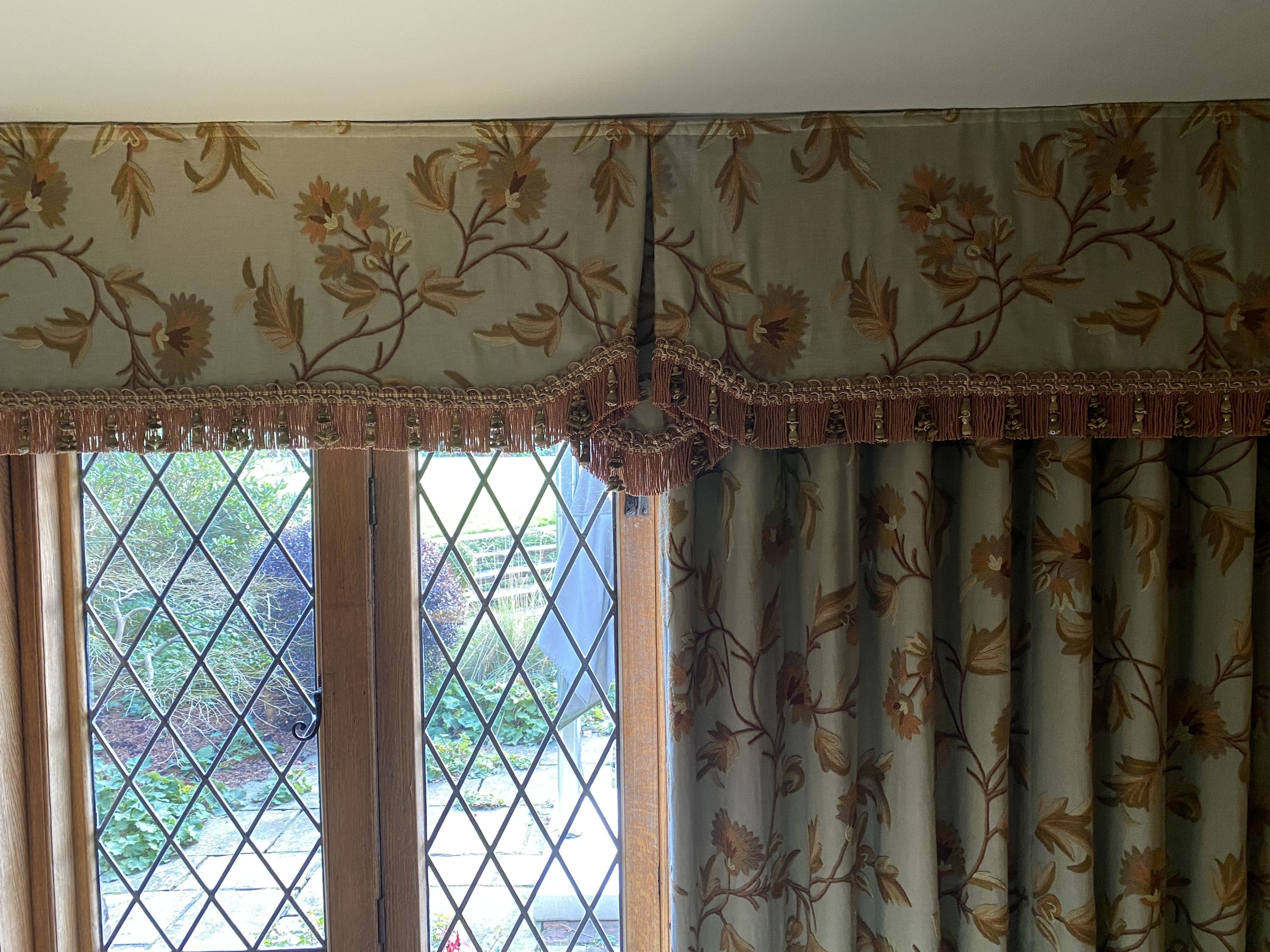 A pair of eau de nil linen curtains with floral crewel work decoration, and matching two piece pelmet, drop 230cm, generously made to fit an aperture of 3.8m